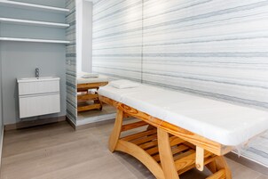 Un baño moderno con un banco de madera, un lavamanos y una pared de mármol.
