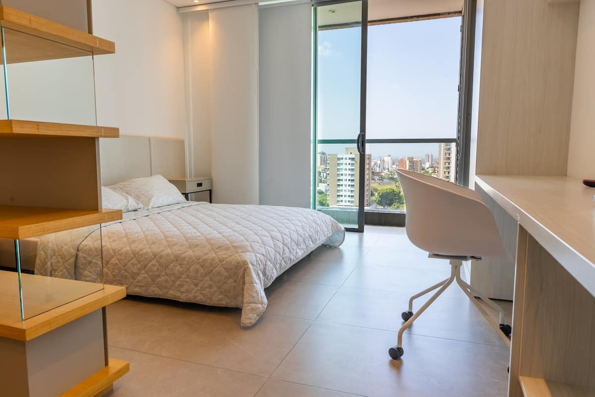 A modern bedroom with a bed, a desk, and a chair.