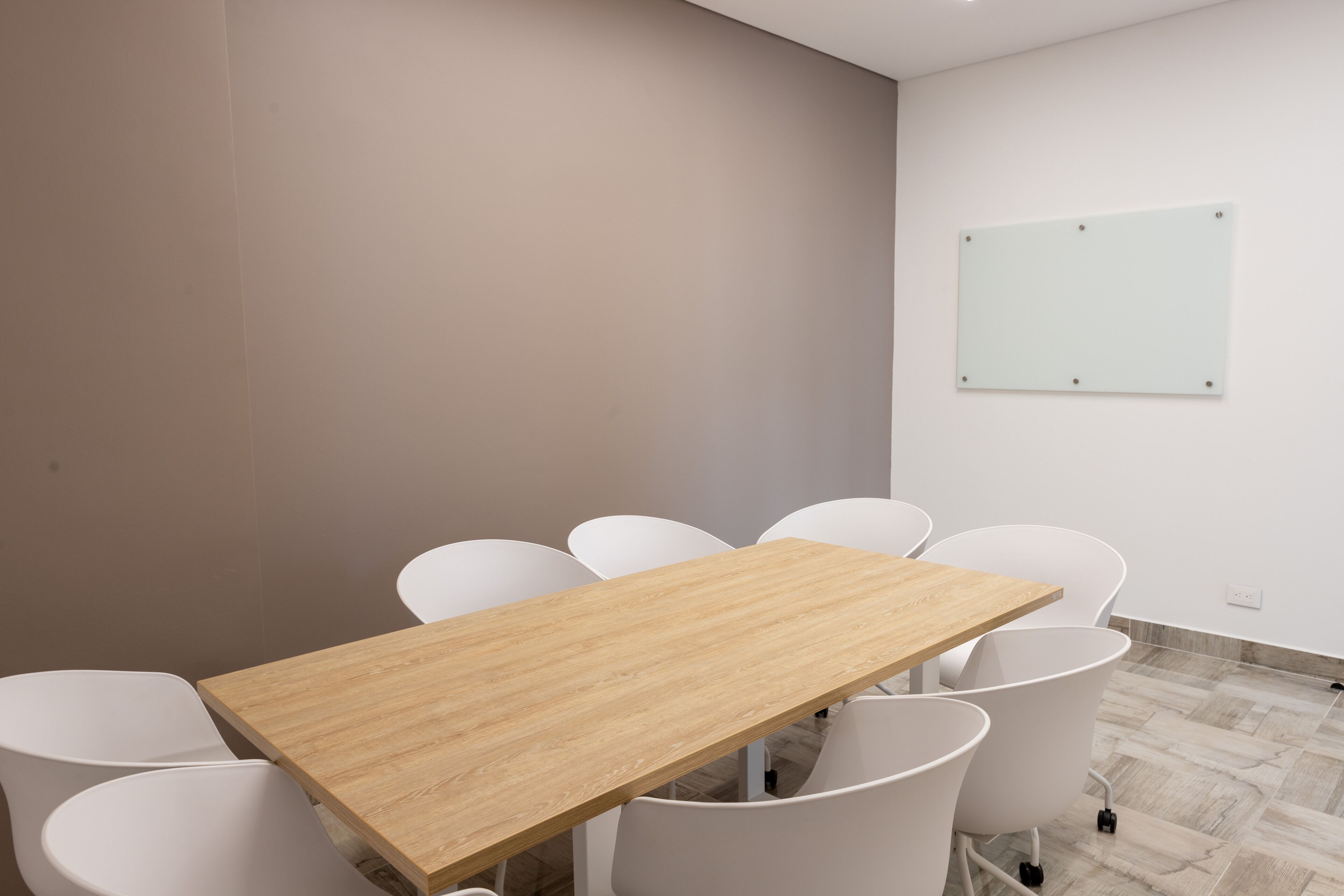 Un salón de conferencias con una mesa de madera y sillas blancas.