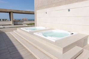 Two hot tubs on a rooftop terrace with a view of the sea and buildings in the background. - distrito 90 (Barranquilla)