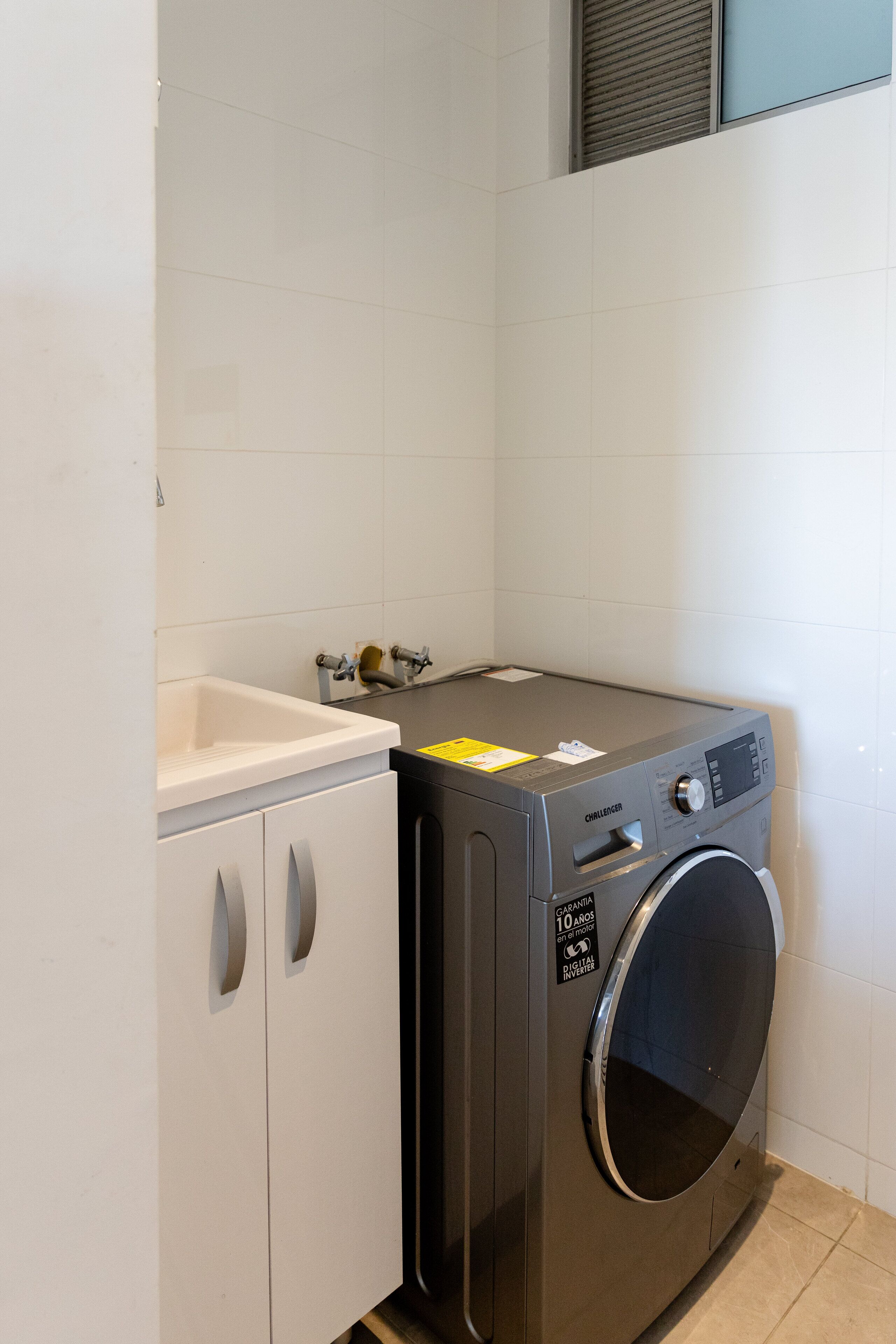 A compact laundry area with a washing machine, a sink, and a cabinet.