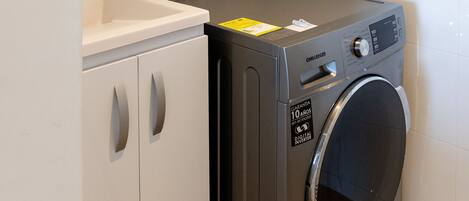A compact laundry area with a washing machine, a sink, and a cabinet.