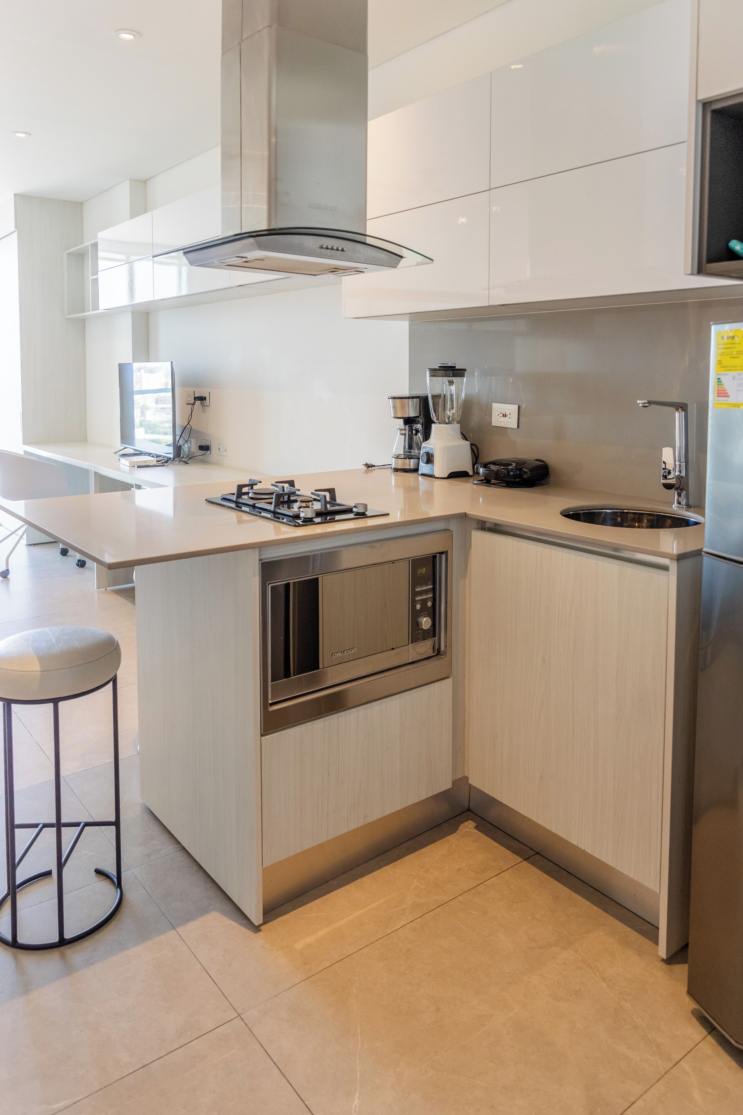 Een moderne keuken met een centraal eiland, roestvrijstalen apparatuur en een groot raam voor natuurlijk licht.