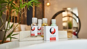 Un meuble-lavabo de salle de bain avec une plante en bambou, trois bouteilles de gel douche et une boîte de bonnets de douche.