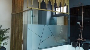 Une salle de bain moderne avec une grande baignoire, des panneaux muraux en bambou et une cloison en verre.