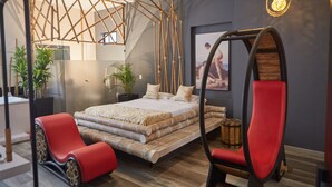 Une chambre à coucher moderne avec un lit, des chaises rouges et un plafond au motif géométrique.