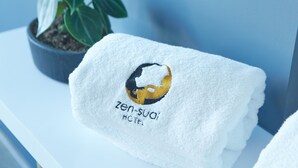 Une serviette blanche ornée d’un logo et d’une inscription indiquant qu’elle provient de l’hôtel Zen-Sual.