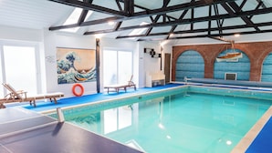 An indoor swimming pool with a blue floor, a wooden bench, and a life ring. - 2 Bed Barn conversion (Tibenham)