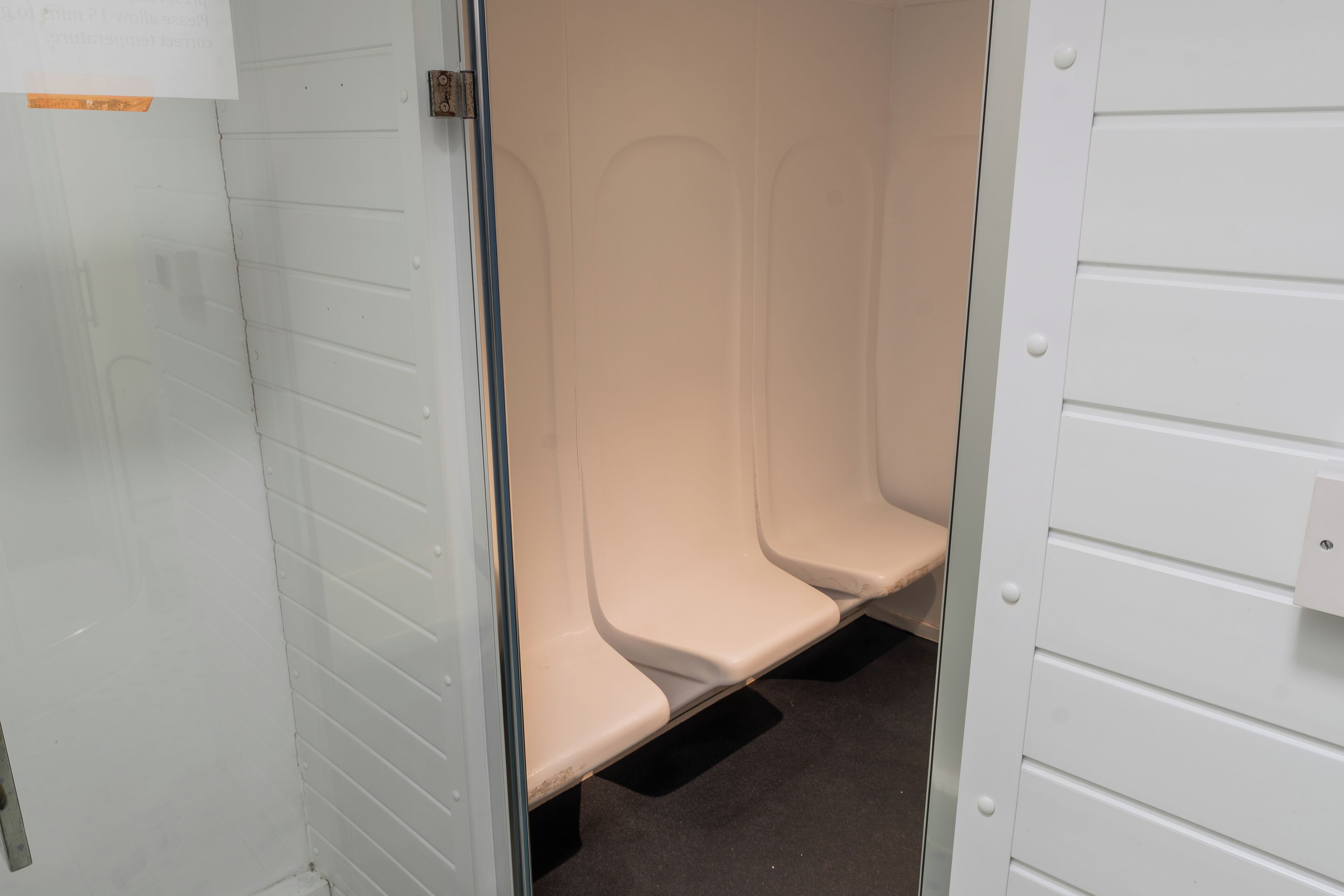 A restroom with three white sinks and a black floor.