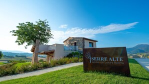 Een bord voor 'Serrre Alte Landscape Luxury Rooms' met uitzicht op een modern gebouw en een boom op de voorgrond.