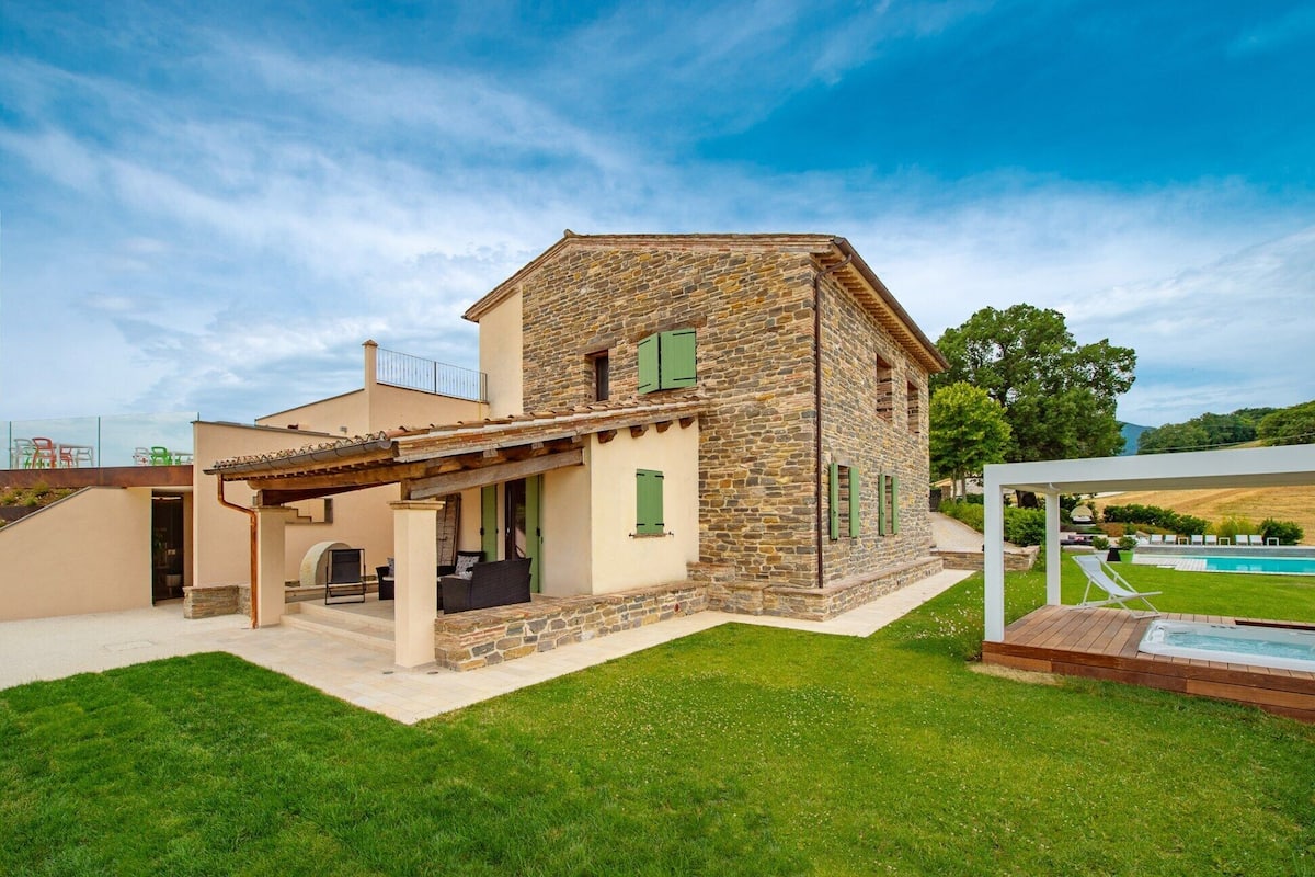 Une maison en pierre dotée d’un patio couvert et d’une piscine.