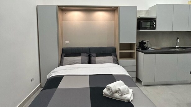 A compact hotel room with a bed, a small kitchenette, and a built-in wardrobe. - Gabry's House-Apartment equipped with all amenities in the center of Naples. (Napoli)