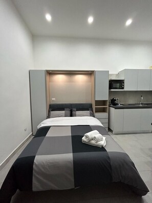 Ein kleines Hotelzimmer mit einem Bett, einer kleinen Küchenzeile und einem eingebauten Kleiderschrank.