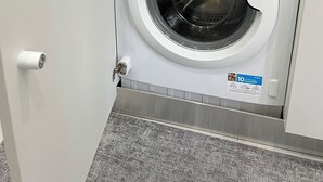 A compact washer and dryer unit with a control panel, a coffee maker, and kitchen utensils on the countertop. - Gabry's House-Apartment equipped with all amenities in the center of Naples. (Napoli)