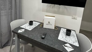 A modern room with a flat-screen TV mounted on the wall, a table with two chairs, a coffee mug, a remote control, and a box labeled "A Filialetta". - Gabry's House-Apartment equipped with all amenities in the center of Naples. (Napoli)