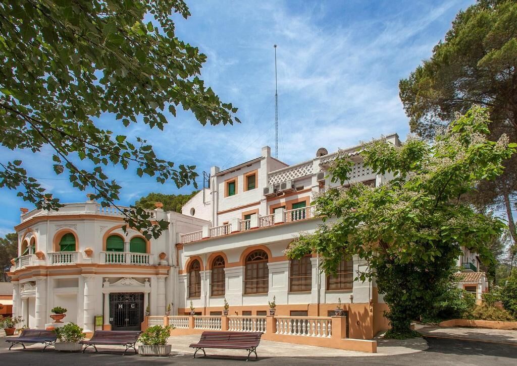 Un edificio histórico con fachada simétrica, ventanas en arco y una entrada central.