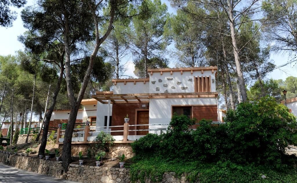 Una casa moderna de dos pisos con cimientos de piedra, detalles de madera y un balcón.