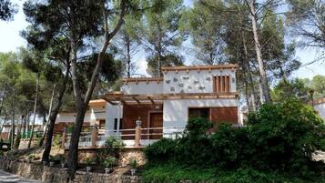 Una casa moderna de dos pisos con cimientos de piedra, detalles de madera y un balcón.