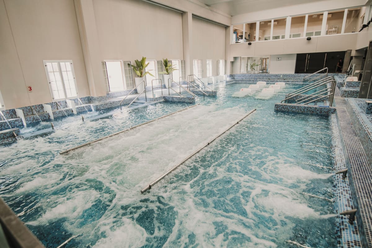 Una piscina interior con varias pistas de natación, un separador central y escalones de acceso al agua.