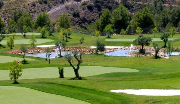 A golf course with multiple green fairways, sand bunkers, and water hazards.
