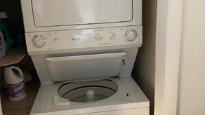Una rentadora i assecadora blanca i compacta de dues portes en un petit espai de bugaderia.