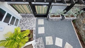 Une terrasse sur le toit agrémentée d’une pergola, de plantes en pot et d’un mur en pierre.
