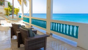 A balcony with wicker furniture, a view of the sea, and a tiled floor.