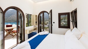 Una camera da letto con un letto, vista sul mare e un balcone con tavolo e sedie.