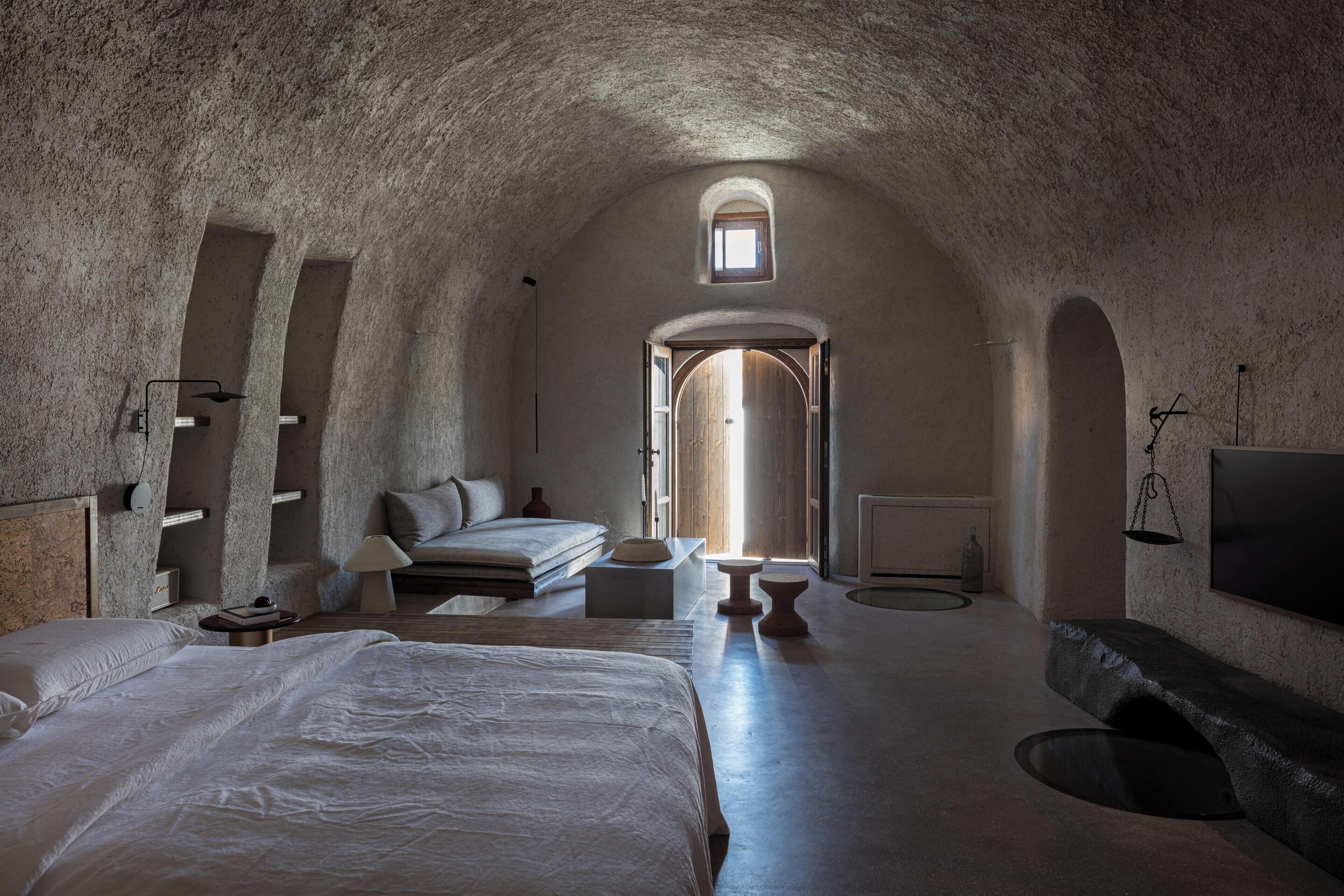 A spacious, arched room with a large bed, a sofa, and a small table.
