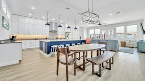 Una cocina amplia con armarios blancos, una isla azul e iluminación colgante.