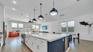 Una cocina amplia con una isla grande, iluminación colgante y vistas al exterior.
