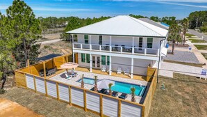 Una casa de dos pisos con piscina y zona de estar al aire libre.