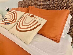 A bed with white bedding and two decorative pillows with abstract patterns. - Studio Charm w/ Deck, Fireplace & Fooseball!: Walk to Beach, Boardwalk & Dining! (Ocean City)