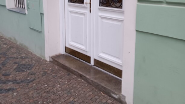 Een gevel met groen, witte deuren en een metalen hekwerk.