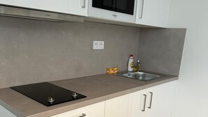 Een moderne keuken met witte kasten, een roestvrijstalen spoelbak en een inbouwoven.