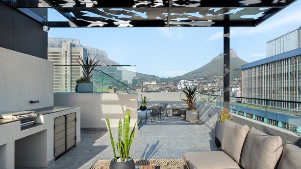 A rooftop terrace with a modern outdoor kitchen, seating area, and potted plants. - Stylish Minimalist: The Tokyo|Mountain and City View (Cape Town)