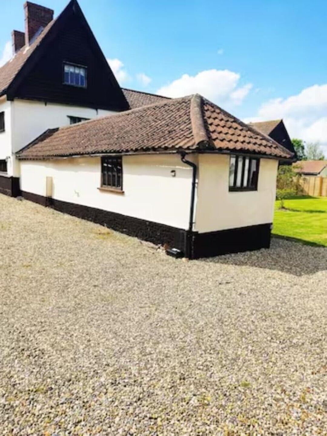 Een huis met pannendak, klein raam en een grindpad.