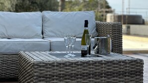 A wicker table with a bottle of wine, glasses, and a metal container. - Villa de 220 m2 Avec Piscine et vue mer à 5min des Plus Belles Plages de Balagne (L'ile-Rousse)