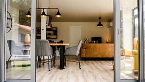 Eine moderne Küche mit Essbereich, inklusive Holztisch, grauer Stühle und Pendelleuchten.