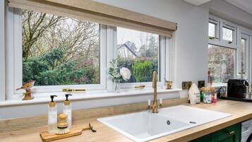 A modern kitchen with a large window, a white sink, and wooden countertops.