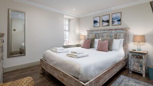 Un dormitorio con una cama grande, un espejo y tres cuadros colgados en la pared.