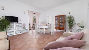 Un salón amplio con mesa de comedor, sofás blancos y televisor.