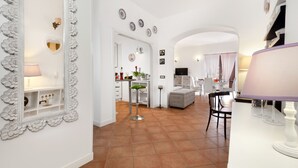 Un salón espacioso con un sofá blanco, una mesa de comedor y una cocina al fondo.
