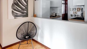 Een modern interieur met een visgraat parketvloer, een zwarte draadstoel en een groot abstract kunstwerk aan de muur.