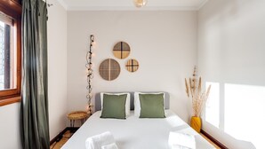 Een slaapkamer met een groot bed, twee kussens, een nachtkastje, een lamp en decoratieve wanddecoratie.