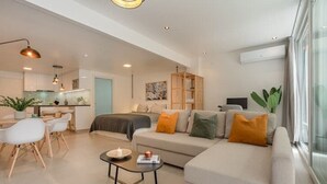 A modern living room with a sofa, coffee table, and dining area. - King-size bed with terrace and Air Conditioning!
 (Las Condes)
