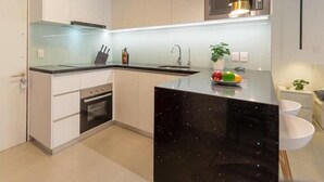 A modern kitchen with white cabinets, a black marble island, stainless steel appliances, and pendant lighting. - King-size bed with terrace and Air Conditioning!
 (Las Condes)