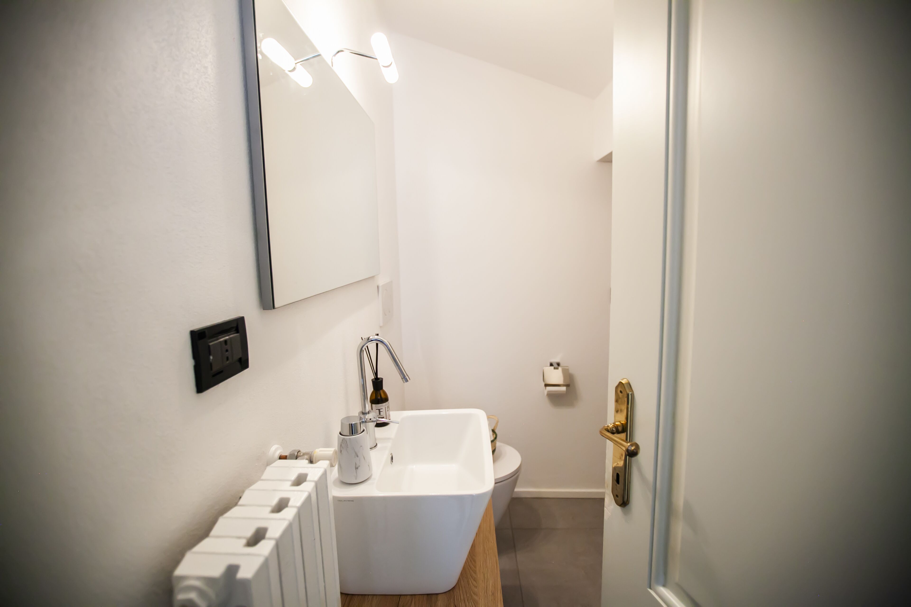 Un baño moderno con un lavamanos blanco, un espejo y un inodoro.