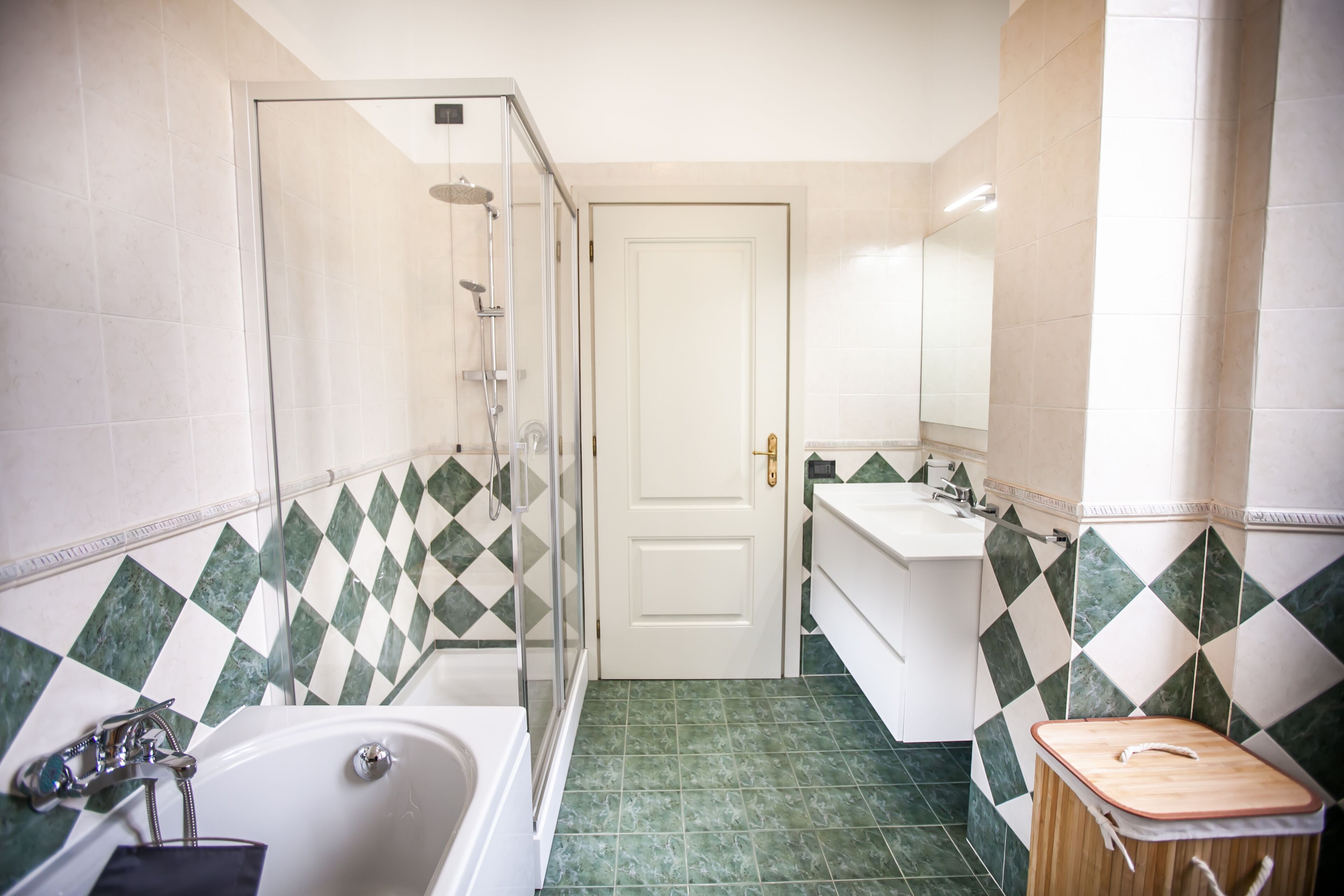 A bathroom with a glass-enclosed shower, a bathtub, a sink, and a mirror.