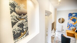 A hallway with a traditional Japanese wave painting, a modern sofa, and a colorful abstract painting on the wall.